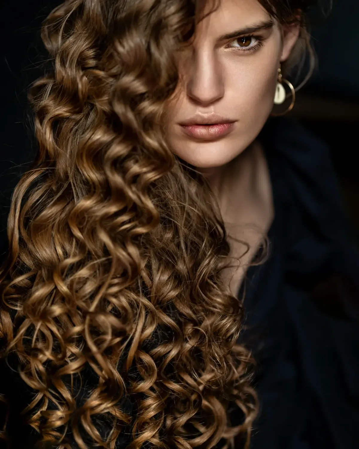 Frau mit langen Locken und goldenem Ohrring