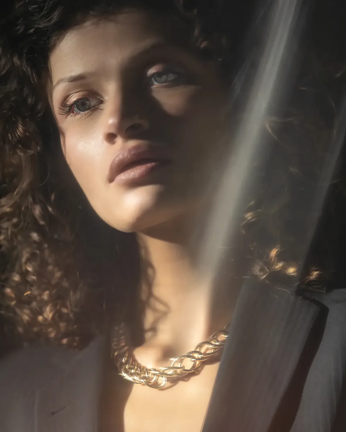 Frau mit Locken und Goldkette im Streiflicht