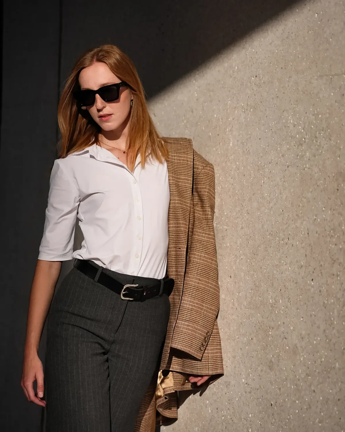 Model mit Sonnenbrille und Blazer über der Schulter im Abendlicht